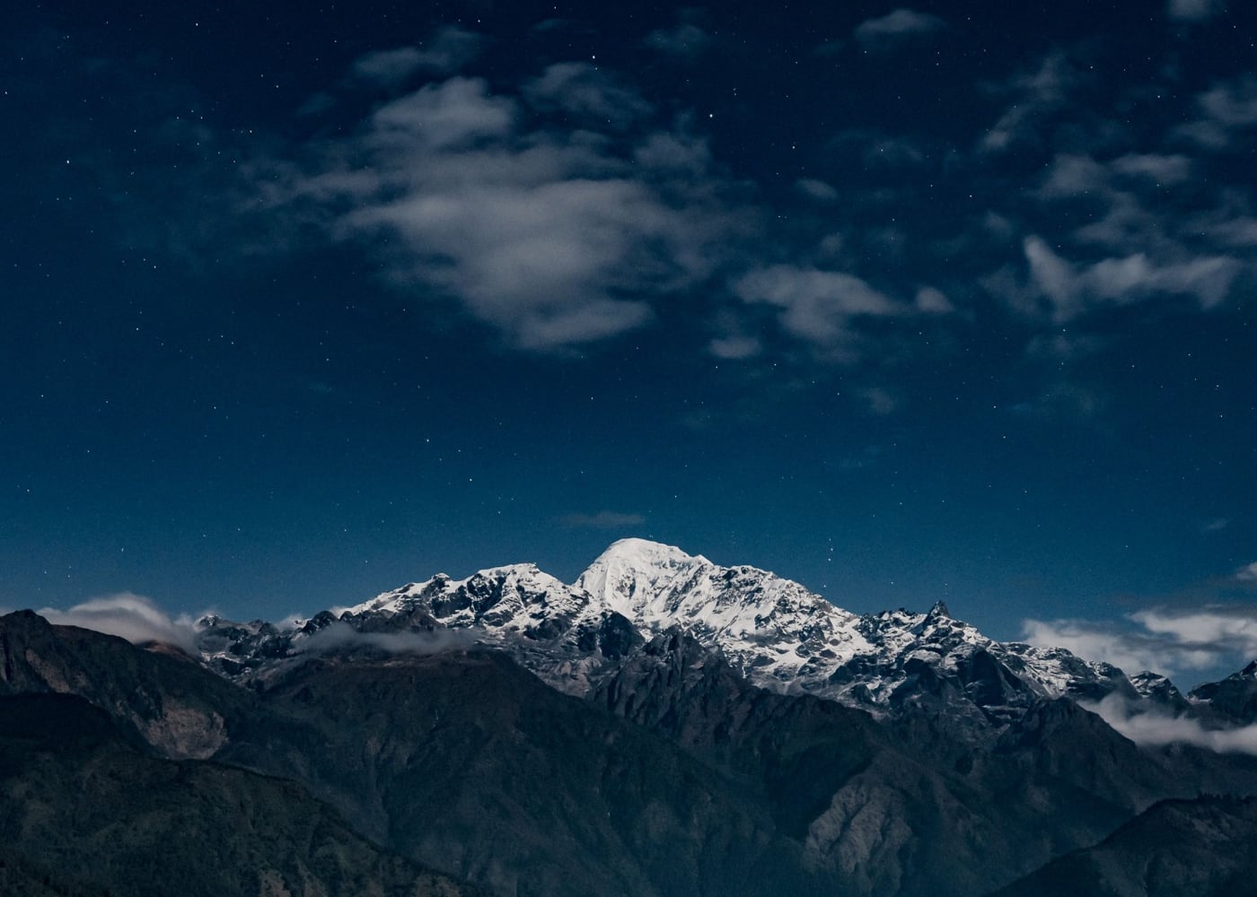 Schneebedeckter Berggipfel bei Nacht unter Sternenhimmel